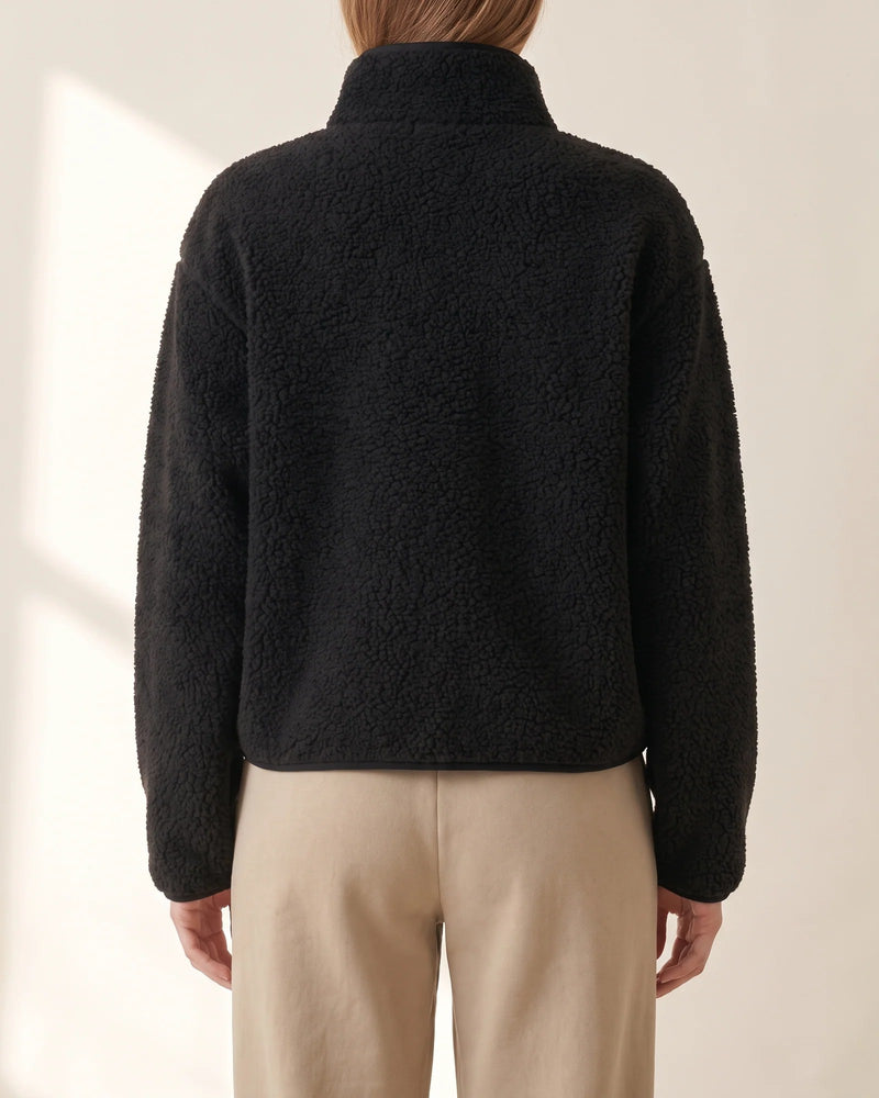 Back view of the black sherpa half-zip showing the funnel collar, dropped shoulders and cropped hem