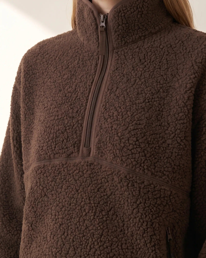 Close view of the chocolate sherpa half-zip showing the tall funnel collar, the tonal zip and the curved chest seam