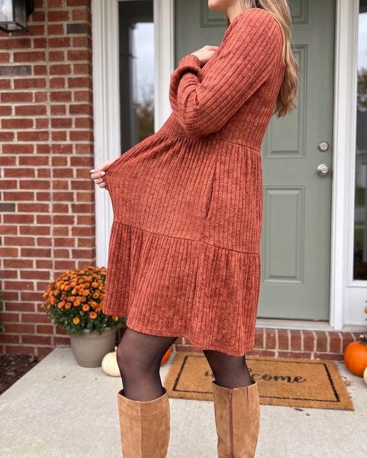Rust sweater dress pulled out from the tummy to show how far the soft rib knit stretches