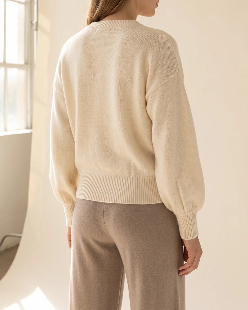 Back view of the cream wrap sweater showing the sleeves and ribbed waistband