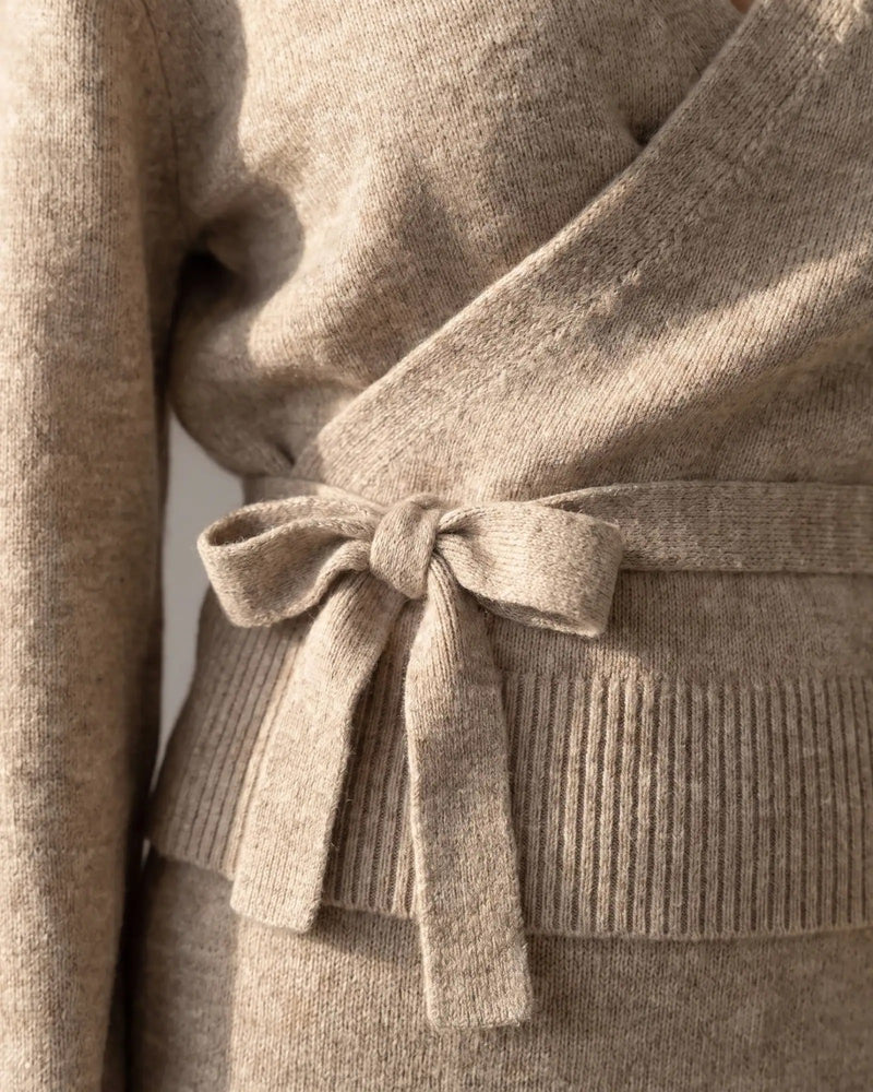 Close view of the self-tie bow at the side of the waist of the oatmeal wrap sweater