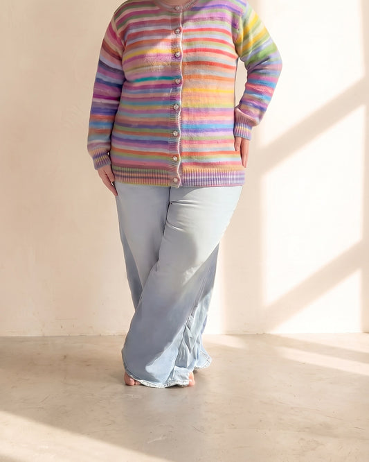 Plus-size woman wearing the rainbow cardigan buttoned over wide-leg jeans, hem at the hip