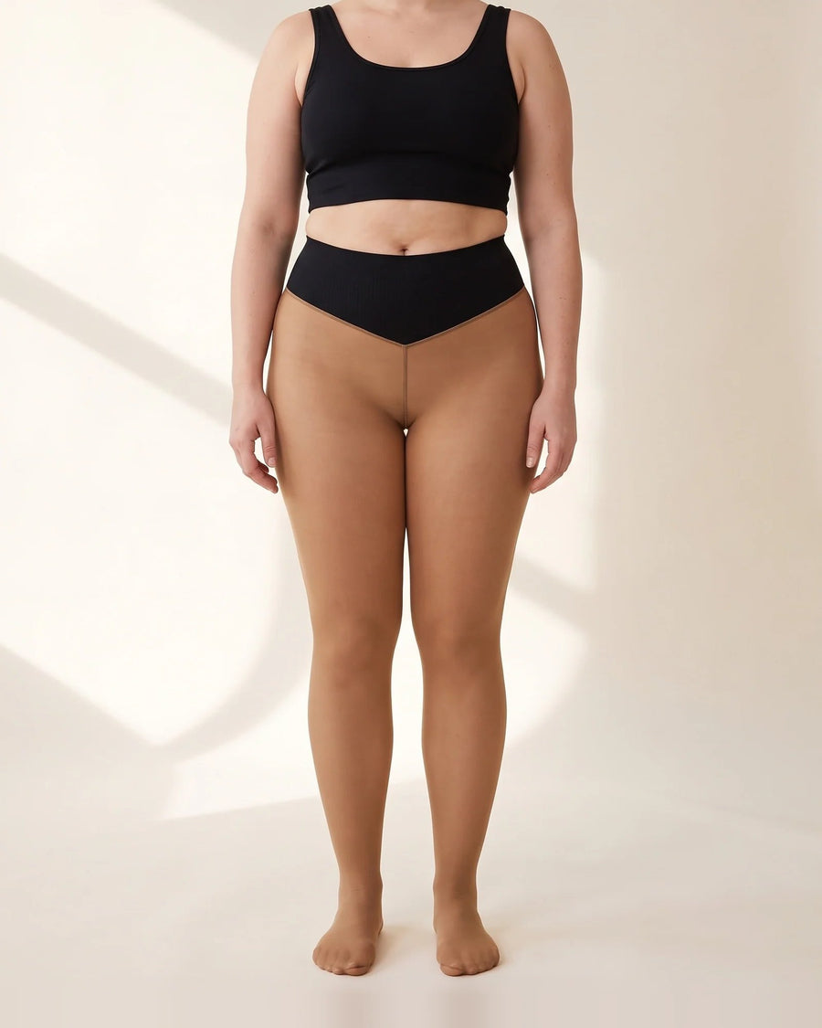 Woman in the tan Willow shapewear fleece tights, the black shaping band across her belly button dipping to a V