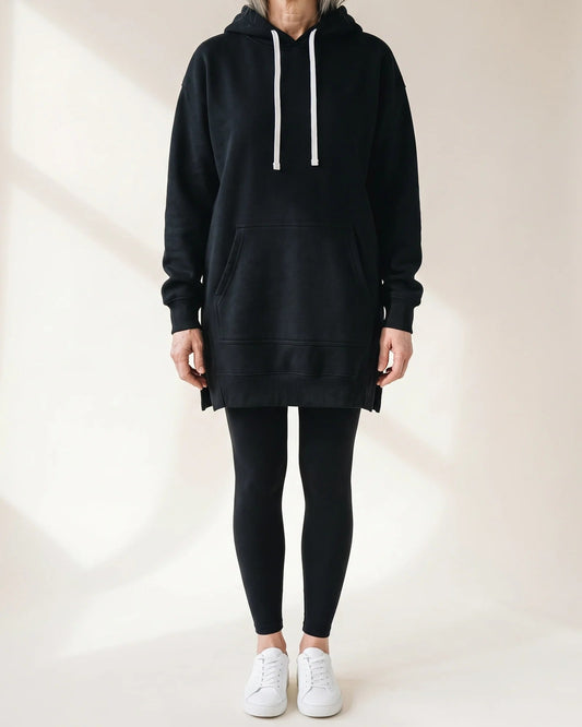 Black oversized hoodie dress with white drawcords and a kangaroo pocket, worn with black leggings