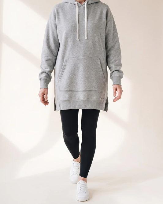 Grey hoodie dress worn mid-stride, the side slit opening at the ribbed hem